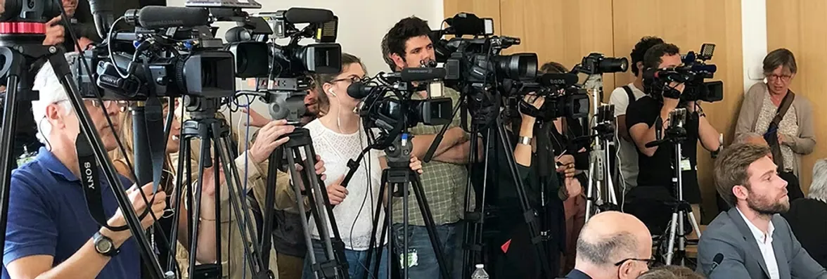Rangée de caméras et de journalistes lors d'une conférence de presse internationale traduite en simultané